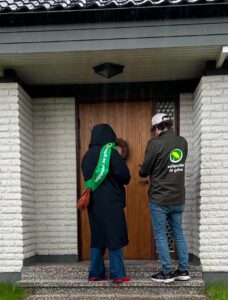 Två personer från miljöpartiet knackar på en dörr.