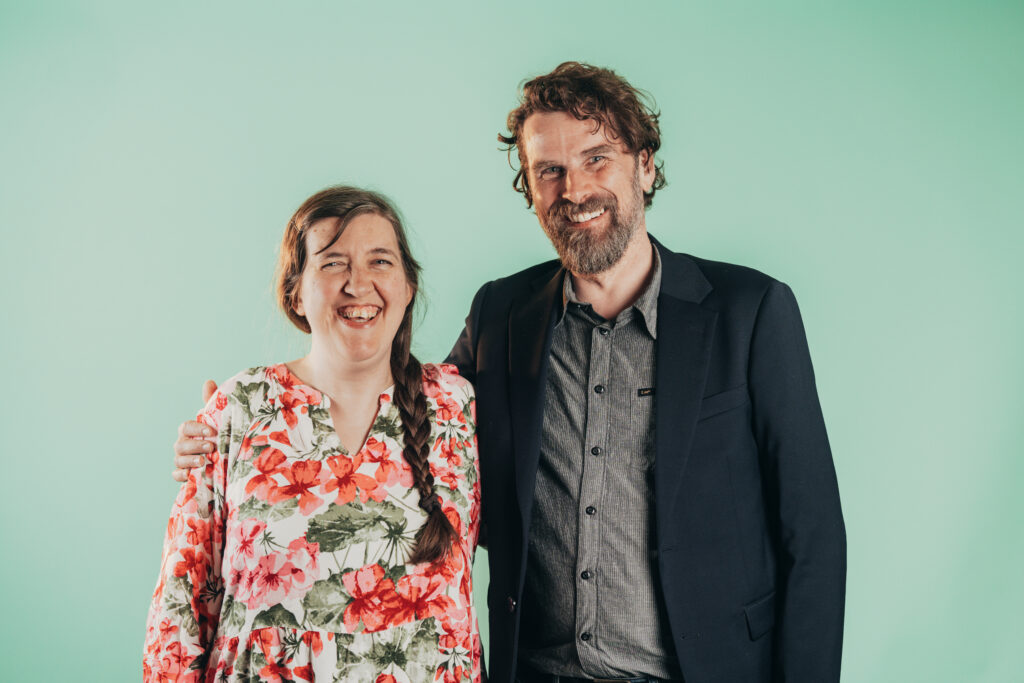 Miljöpartiets båda språkrör i Skövde, Elisabeth Brunnegård och Johan Örnemar står leende bredvid varandra.