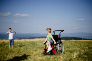 Pojke i rullstol ute i naturen med sin vän