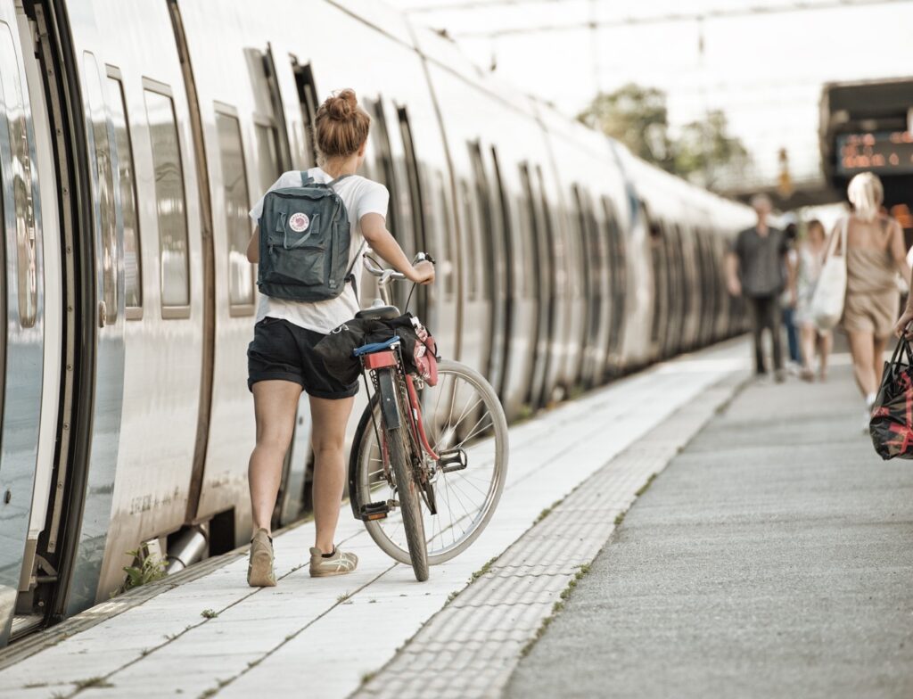 Kvinna promenerar cykel bredvid pendeltåg