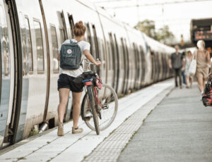 Tjej som går med cykel på perrong