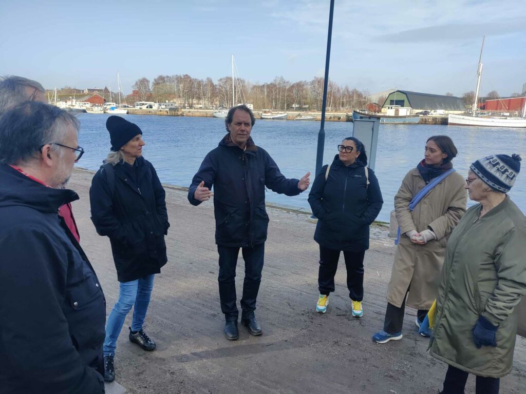 Pär Holmgren talar engagerat om klimatutmaningar med lokala miljöpartister och kommunala tjönstepersoner invid Nissan i Halmstad