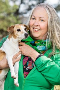 Vårt andranamn Anna-Karin Sandberg står och håller sin hund Hippi under armen.