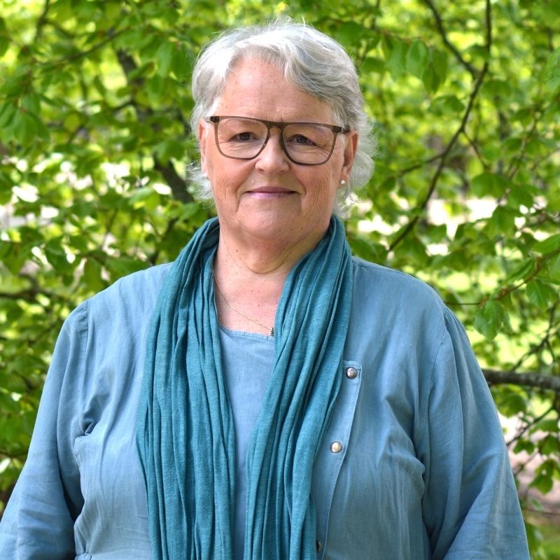 Porträtt av Lena-Maj Anding utomhus framför grön lövskog.