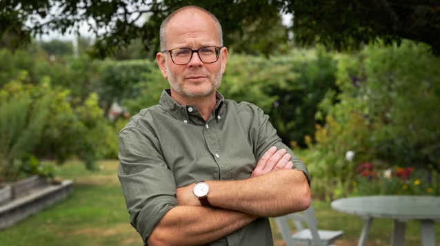 Johan står med armarna i kors och tittar in i kameran.